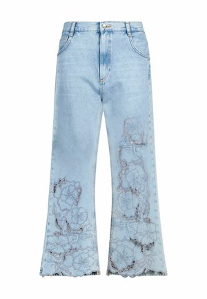 Hellblaue Jeans aus Denim mit ausgestellten Beinen und floraler Spitze mit ausgeschnittenem Stickmuster an beiden Beinen nahe dem Saum.