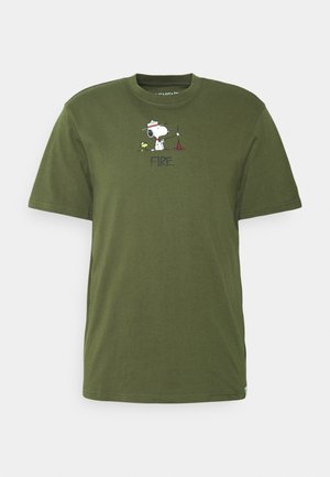 T-shirt vert olive avec Snoopy portant un chapeau de ranger, debout à côté de Woodstock et d'un petit feu rouge, légendé "FEU."