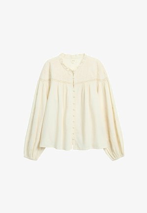 Cremefarvet bluse med rund halsudskæring, knaplukning foran og lange, voluminøse ærmer. Har tekstureret stof og blonde detaljer.