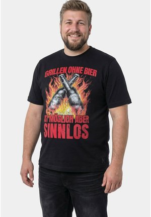Lächelnder Mann mit schwarzem T-Shirt, auf dem zwei gekreuzte Bierflaschen über Flammen und rotem deutschen Text zum Grillen und Bier abgebildet sind.