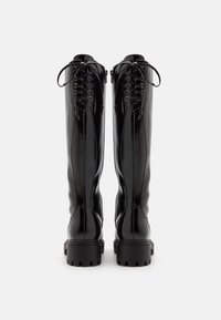 Stivali alti fino al ginocchio neri, stringati, con finitura lucida, pelle testurizzata, cuciture in evidenza e suole in gomma spesse.