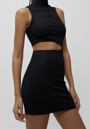 Black ribbed crop top with high neck and sleeveless design, paired with a fitted black mini skirt, both made from stretchy fabric.