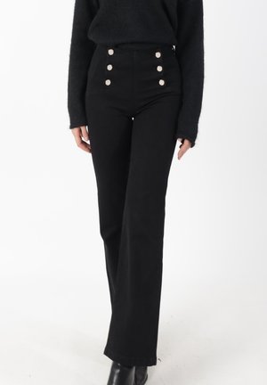 Pantalones negros de talle alto hechos de tela resistente, con cuatro grandes botones plateados en la parte delantera y un diseño de pierna recta.