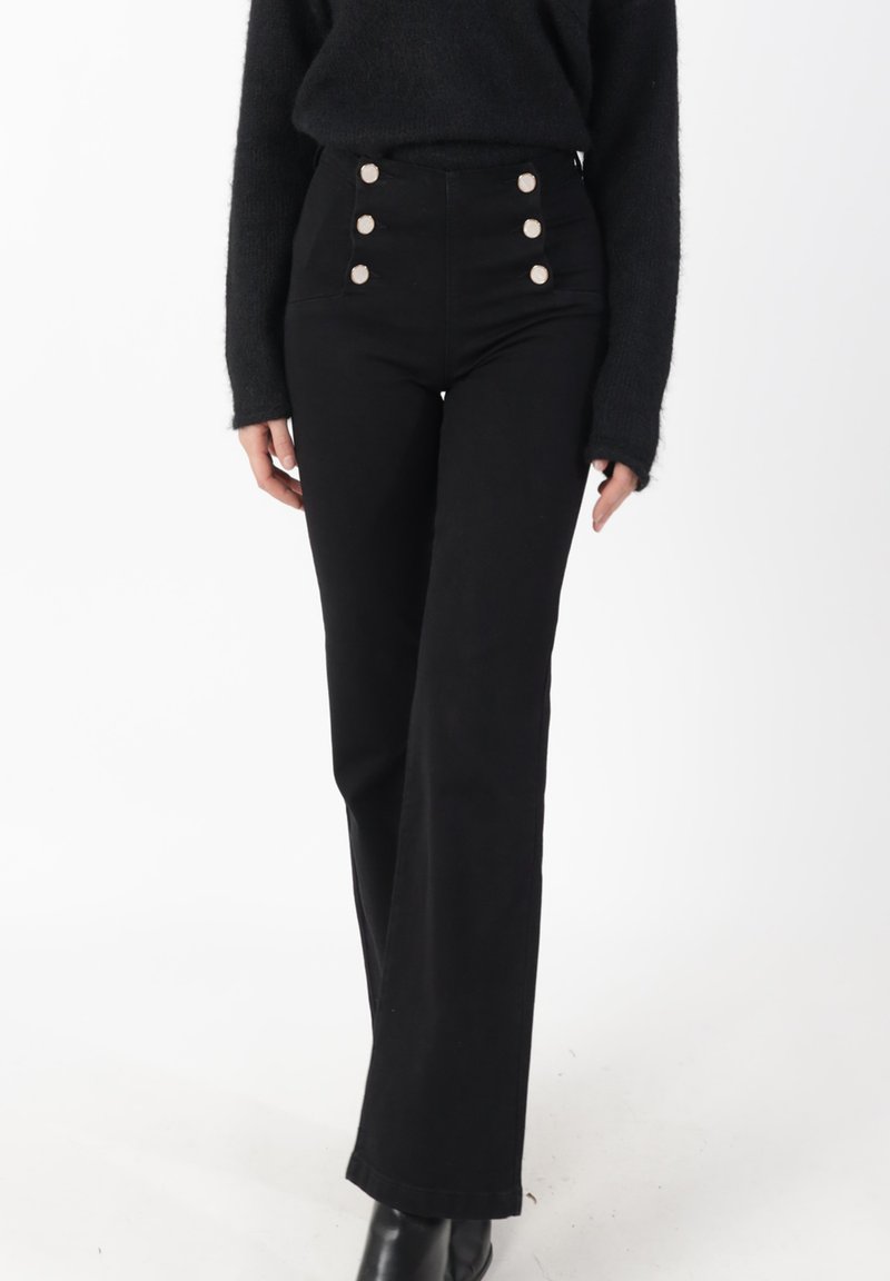 Pantalon noir taille haute en tissu robuste, avec quatre grands boutons argentés sur le devant et une coupe droite.