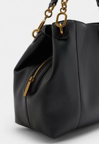 Sac à main en cuir noir avec une finition texturée, ferrures dorées, une poche zippée et une chaine en bandoulière. Forme arrondie avec des coutures visibles.