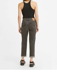 Svarta denimjeans med avsmalnande ben, uppvikta muddar och bakfickor med distinkta sömnads mönster. Bärs med en svart linne.