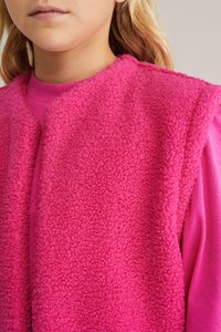 Jasne ružové flísové vesty s textúrovaným povrchom, navrstvené na zodpovedajúcej ružovej košeli s dlhým rukávom. Jednoduchý dizajn, žiadne viditeľné zapínanie.