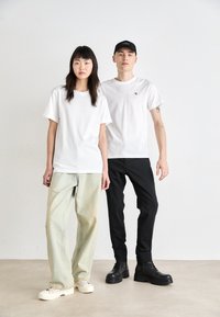 White t-shirts, relaxed fit, paired with light denim and black pants. Footwear includes chunky white shoes and black lace-up boots.