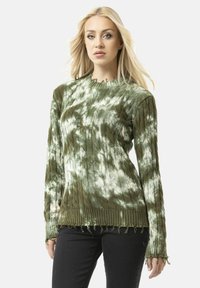 Grüner gestrickter Pullover mit einem Zopfmuster, ausgestattet mit einem gerippten Saum und ausgefranstem Rand. Der Stoff hat einen Batik-Effekt mit helleren Farbtönen.