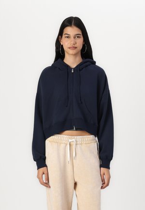 Navy cropped hoodie with a zip front, drawstrings, and two front pockets. Soft material with a relaxed fit and long sleeves.