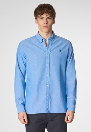 Camicia azzurro chiaro con bottoni realizzata in un tessuto testurizzato, dotata di un colletto classico e un piccolo logo ricamato sul lato sinistro del petto.