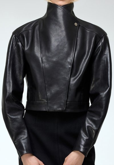 Černá kožená zkrácená bunda s vysokým límcem, asymetrickým předním dílem a viditelnými švy. Hladký povrch a elegantní design.