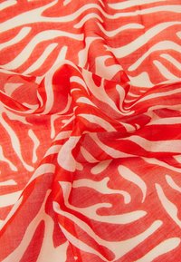 Tissu léger avec des rayures abstraites rouge et blanc rappelant celles d'un zèbre, légèrement froncé pour montrer la texture et le flux du motif.