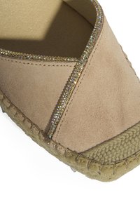 Espadrille en suédine beige avec un design entrecroisé, ornée de strass multicolores le long des bords, et une semelle en jute tissée.