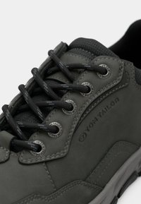 Dunkelgrauer Sneaker aus strukturiertem Leder. Mit schwarzen Schnürsenkeln, Metallösen und "Tom Tailor"-Branding an der Seite. Runde Zehenform.