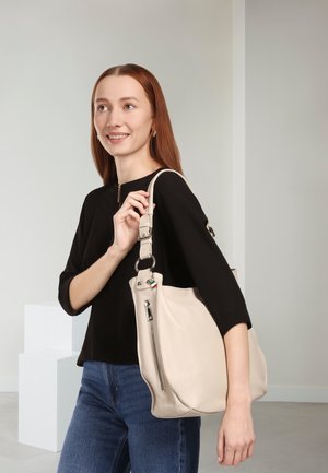 Sac à main en cuir beige avec une finition texturée, doté d'une poche zippée et d'une forme grande et arrondie. Stylisé avec une bandoulière amovible.