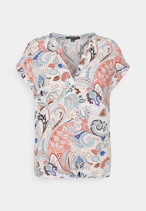 Blouse à manches courtes avec col en V blanche présentant un motif coloré paisley et floral en corail, bleu, marron et noir.