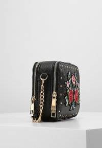 Borsa a tracolla nera in ecopelle con ricami floreali, dettagli in perline dorate, doppie cerniere e una tracolla a catena. Design quadrato compatto.