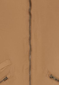 Beige jack met een centrale rits, twee zijzakken met scherpe kleppen en een gladde stofstructuur. Eenvoudig, functioneel ontwerp.