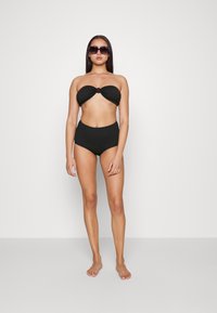 Conjunto de bikini preto com um top sem alças e detalhe em nó, e parte de baixo de cintura alta. Tecido suave, design minimalista, sem padrões.