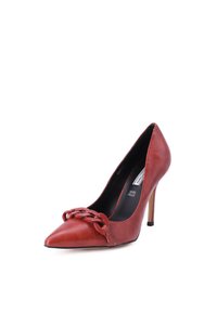 Scarpa con tacco alto in pelle rossa, dalla punta affusolata, caratterizzata da un dettaglio in catena nella parte anteriore e un tacco a stiletto. Texture liscia, design elegante.