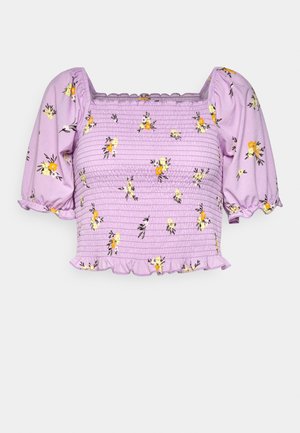 Lilla blomstret top med puffærmer, smocked tekstur og en flæsekant. Har gule og sorte blomstermønstre på blødt stof.