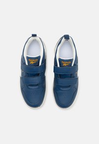 Modré kožené tenisky s páskami na suchý zips, biele vnútorné vyšívanie, perforovaná oblasť pri špičke a žlté logo Reebok na jazyku.