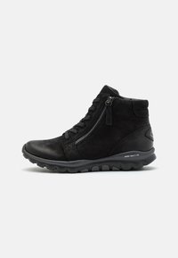 Bottines noires en suede et cuir, avec une fermeture éclair et des lacets, dotées d'une semelle en caoutchouc texturé et d'un design athlétique.