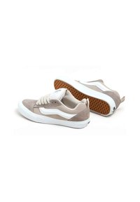 Zapatillas de ante beige con acentos blancos, puntera redonda, suela plana de goma blanca y suela exterior marrón texturizada. Incluyen cordones y una pestaña trasera decorativa.