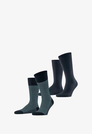 Chaussettes unies bleu marine et chaussettes à motifs teal avec une bordure bleu marine. Les chaussettes ont une texture lisse et sont de hauteurs variées.