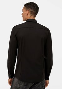 Schwarzes Langarmshirt mit klassischem Kragen, Knopfmanschetten und glatter Textur in taillierter Passform.