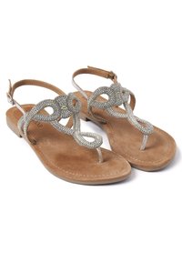 Sandali piatti con una soletta in suede beige, decorazioni in argento sulle cinghie e un design con cinturino tra le dita. Gli accenti presentano motivi intricati.