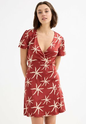 Vestido rojo con un escote en V profundo, mangas cortas y un diseño envolvente. Decorado con patrones de estrellas de mar crema y detalles de botones en el costado.
