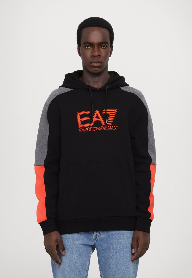 Felpa nera con maniche grigie a contrasto e dettagli arancioni brillanti. Presenta una tasca frontale e il logo ricamato EA7 sul petto.