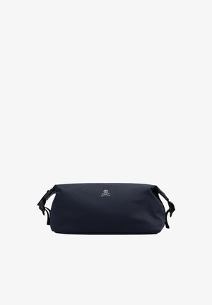 Bolsa de mano de color azul marino, fabricada con material suave, de forma redondeada y con cierre de cremallera, que presenta un logo de calavera y huesos cruzados en plata en la parte frontal.