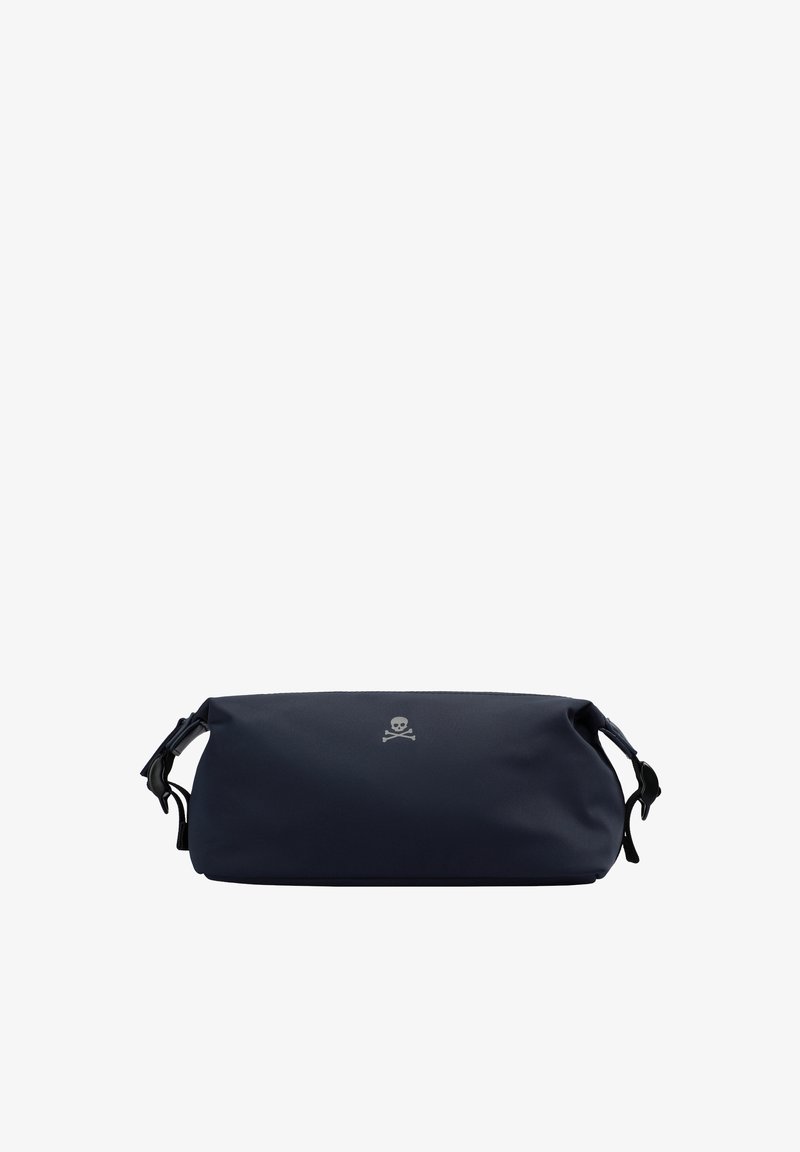 Bolsa de mano de color azul marino, fabricada con material suave, de forma redondeada y con cierre de cremallera, que presenta un logo de calavera y huesos cruzados en plata en la parte frontal.