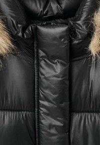Čierna puffr jacket s lesklým povrchom, hrubou kapucňou so syntetickým kožuchom a prešívanými časťami na tepelnú izoláciu. Mäkčená textúra s viditeľnými stehy.