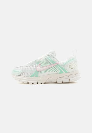 Hvid og mintgrøn atletiksneaker med lyserødt swoosh-logo, mesh-övre, polstret sål og trækkrog på hælen.