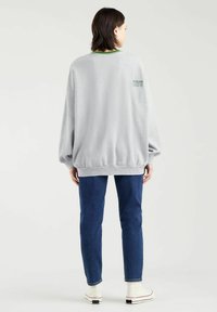 Grå sweater med afslappet pasform, ribbet hals og elastiske manchetter. Har grønne accenter og "Etableret 1873" i broderet tekst.