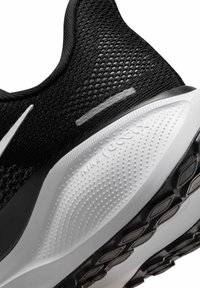 Czarne buty sportowe z oddychającą siateczkową cholewką, białą podeszwą środkową o teksturowanej powierzchni oraz wzorzystą gumową podeszwą zewnętrzną dla lepszej przyczepności.