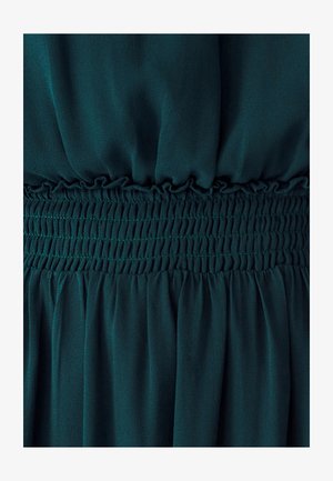 Grøn stof med en glat tekstur, som har samlet smock rundt om taljen og flydende plisseringer nedenfor. Simpelt design uden mønstre.