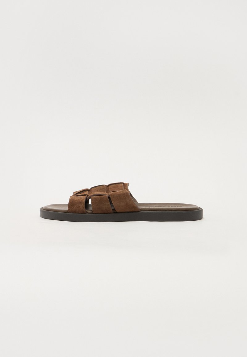 Sandalo slide in suede marrone con ampienuove cinghie intrecciate e suola piatta e testurizzata. Design minimalista con un aspetto casual.