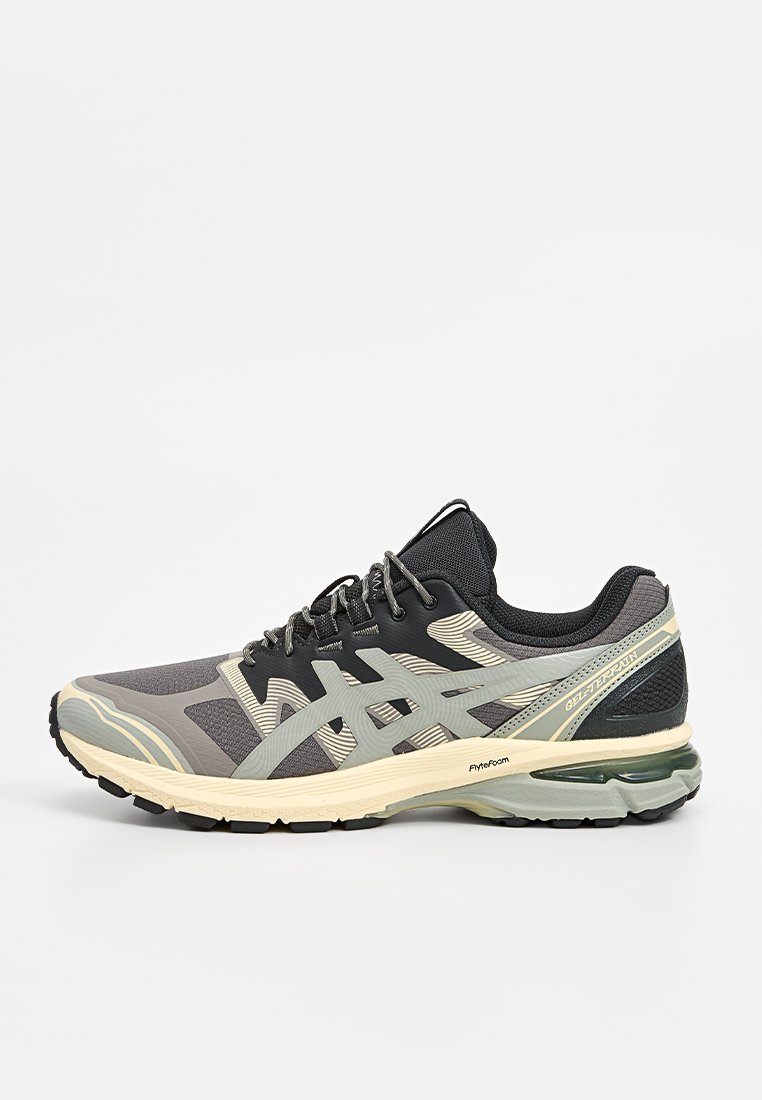 Laufschuh mit einem Design in Schwarz, Grau und Creme. Aus Mesh-Material gefertigt, mit strukturierten Akzenten und einer dicken Gummisohle.