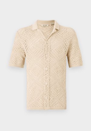 Cardigan en tricot beige à manches courtes avec un motif en losanges, doté d'une fermeture à boutons et d'un col. Fabriqué à partir de matériau léger.