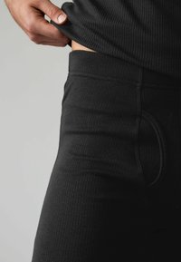 Černé žebrované legíny se slim fit střihem, vybavené hladkým pasem a kapsami na bocích. Texturovaná látka vyzdvihuje flexibilitu.