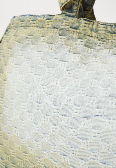 Geantă din denim cu un design texturat în albastru deschis, având un model subtil de hexagoane și o mână întărită.