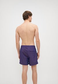 Shorts da nuoto viola con vita elasticizzata e cordoncino, tasca posteriore e materiale leggero.