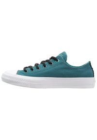 Baskets en toile bleu sarcelle avec des lacets noirs, une semelle en caoutchouc blanche et des panneaux latéraux texturés. Elles présentent un design à coupe basse et un embout renforcé.