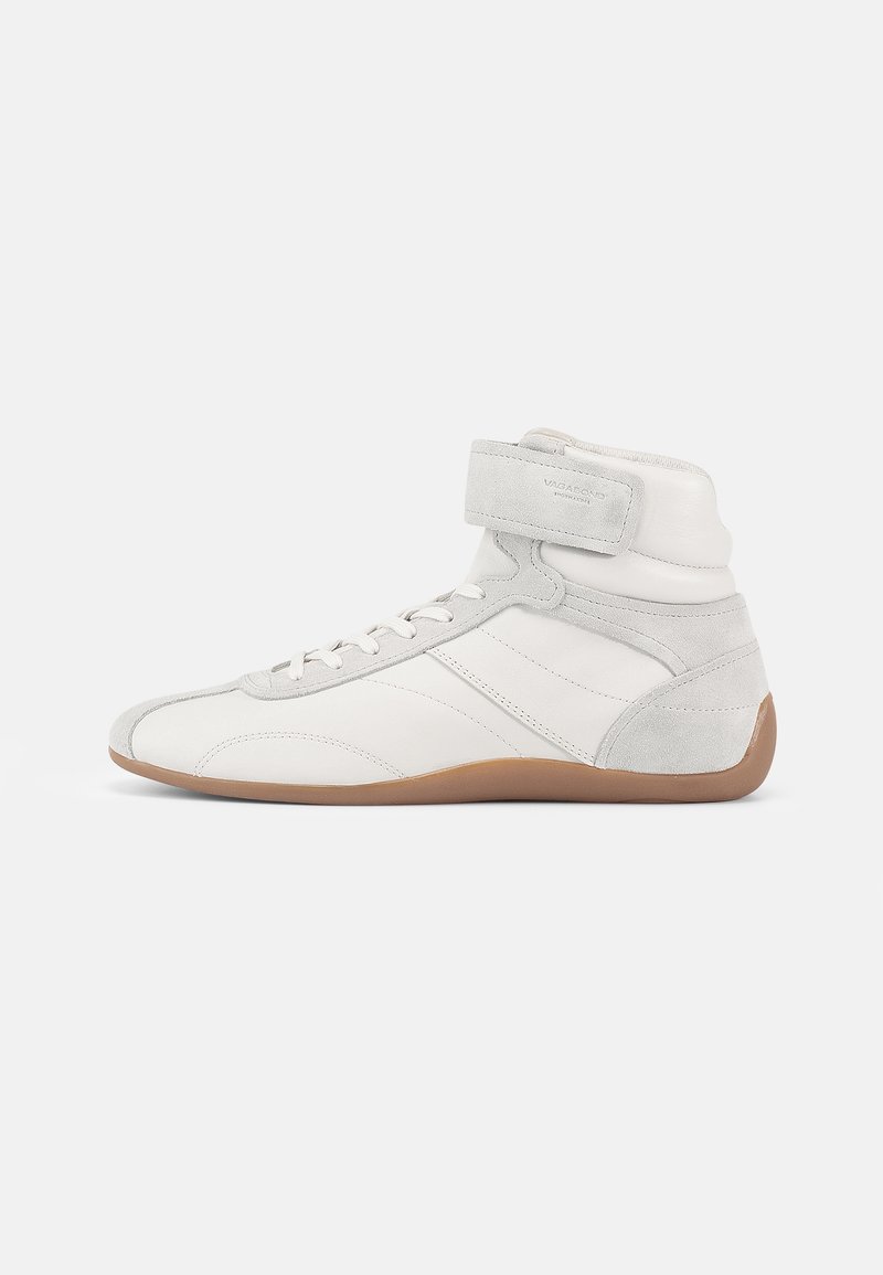 Högklackade sneakers i vitt läder och mocka med beige gummisula. Har snörning fram och ett kardborreband för säker passform.