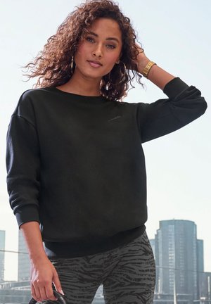 Schwarzer Sweatshirt mit Rundhalsausschnitt und gerippten Bündchen, kombiniert mit gemusterten grauen Leggings, die ein dezentes Zebramuster aufweisen.